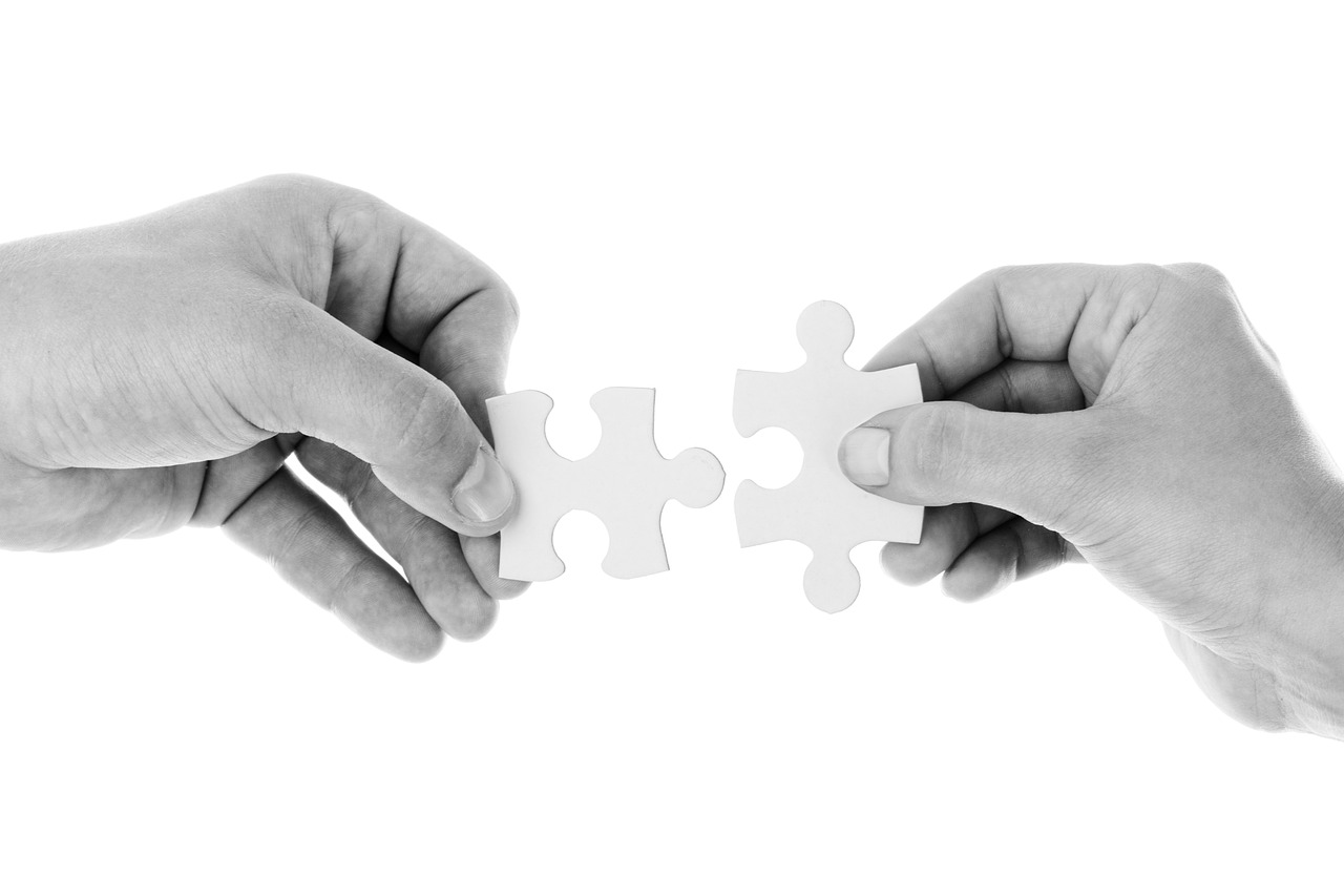 Two hands joining puzzle pieces